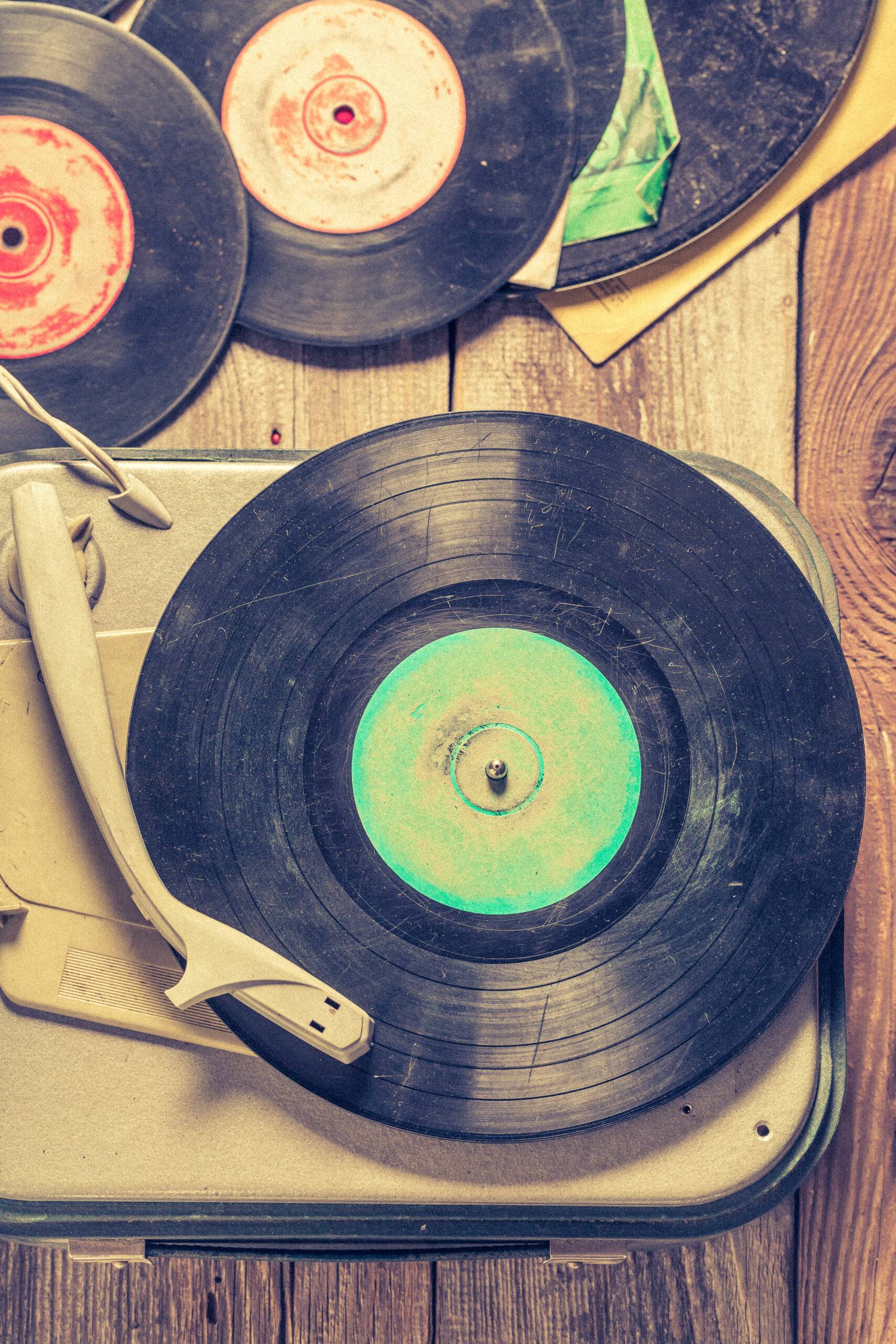 Old gramophone and few vinyl records on wooden table